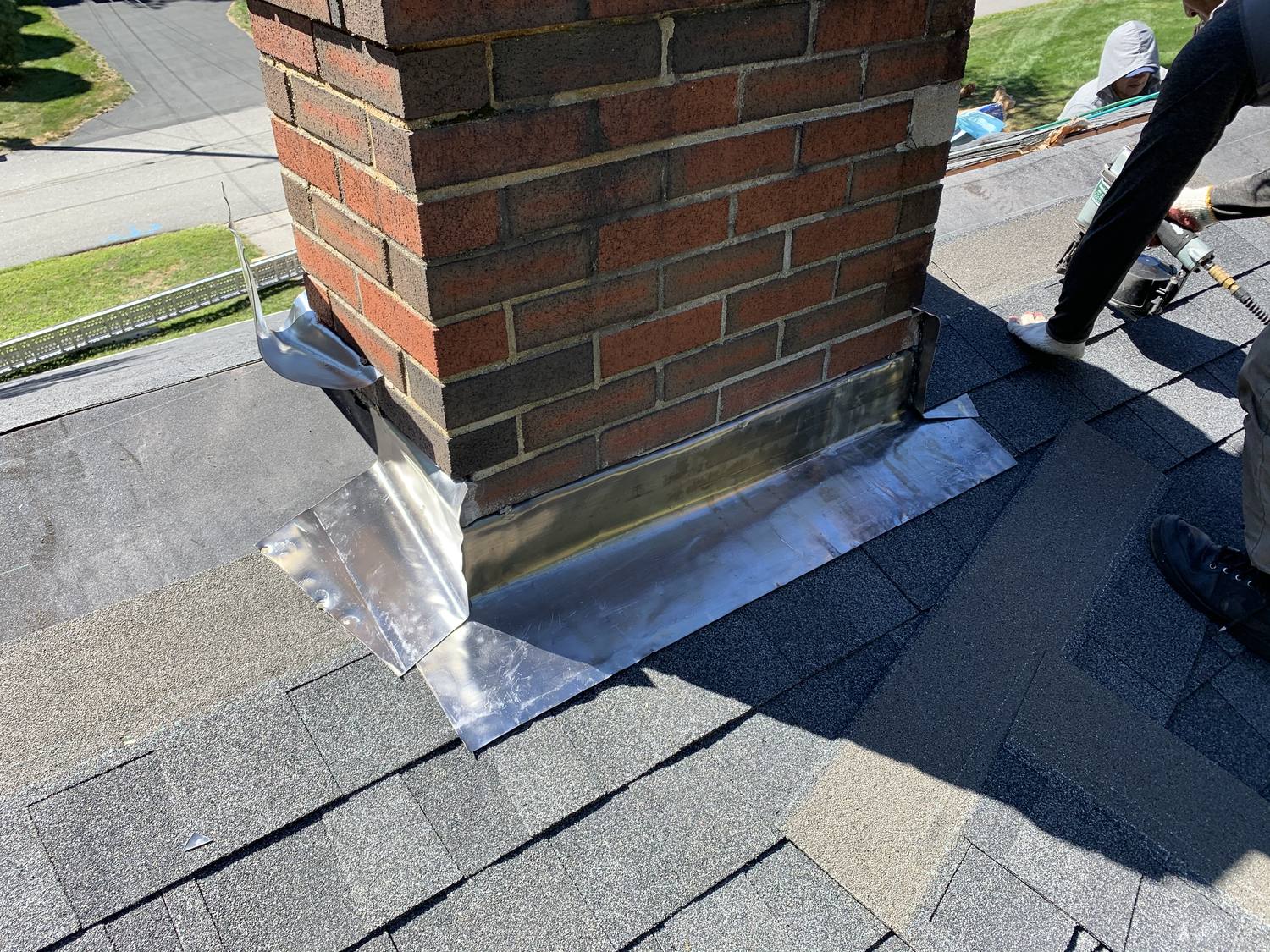 New metal chimney flashing installed around a brick chimney by David Deschaine Roofing in Maine